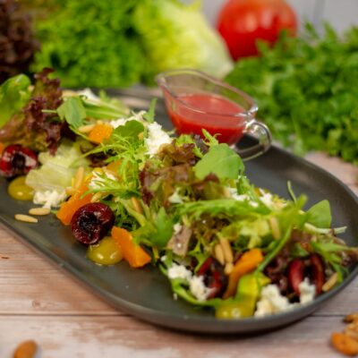 A plate of salad with vegetables and nuts on it